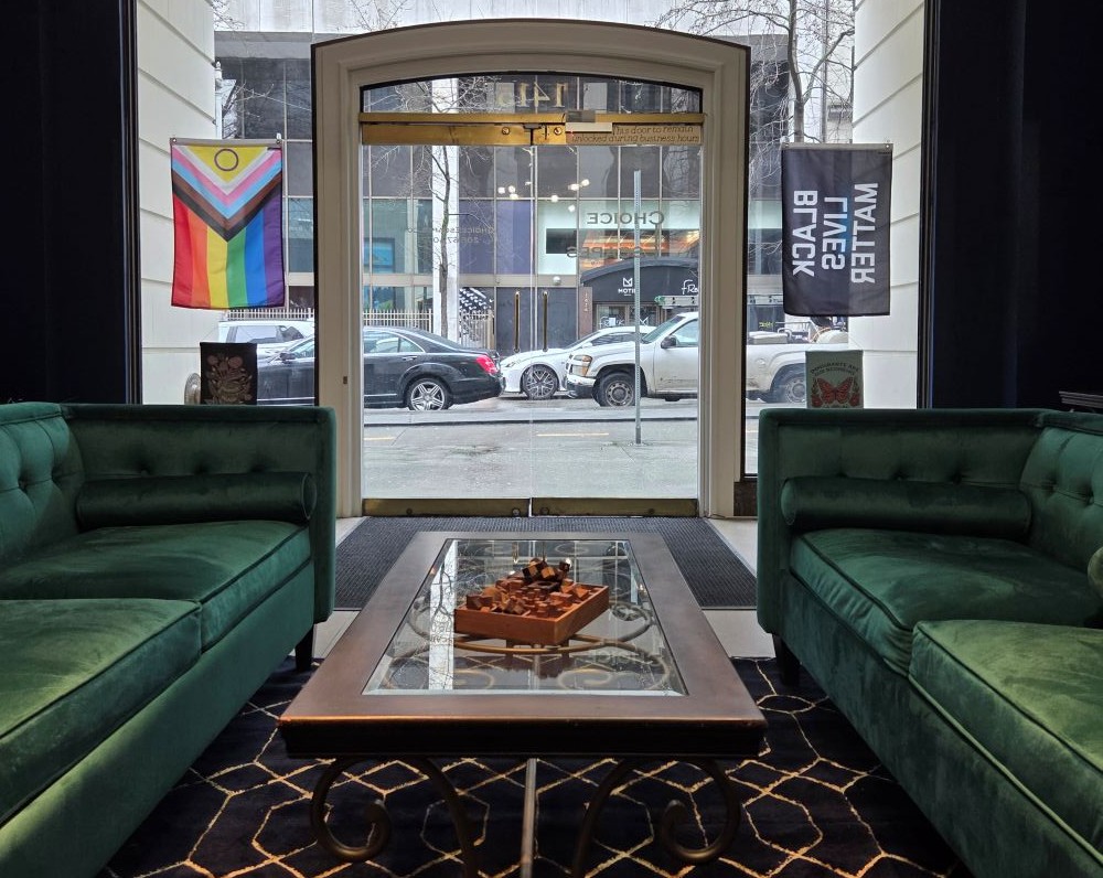 Escape room lobby. Two green couches, a pride flag, and a black lives matter flag.