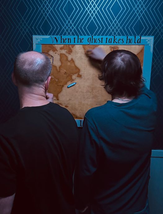 Two people examine a map in the escape room.