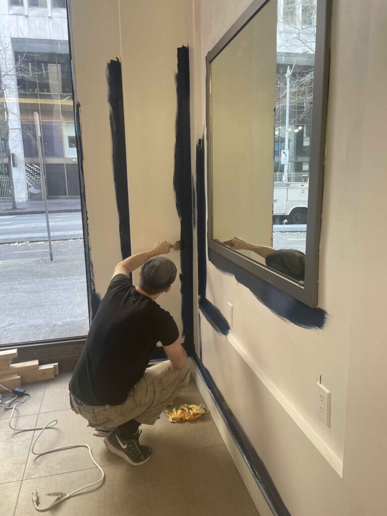 Painting our Seattle escape room lobby. Sean paints a wall blue.
