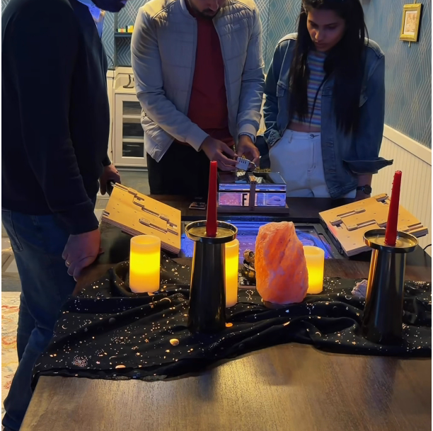 Seattle escape room interior. Candles, a dark cloth, and three people looking at a locked box.